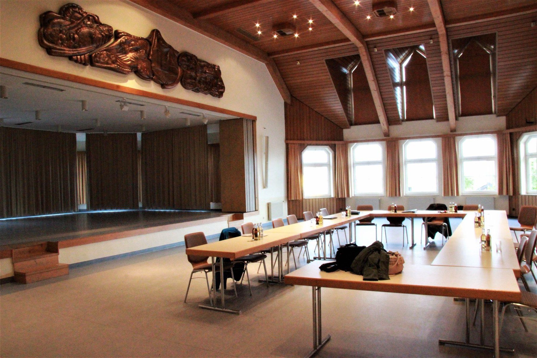 Großer Saal des Gemeindehauses mit Bühne, Tischen und Stühlen